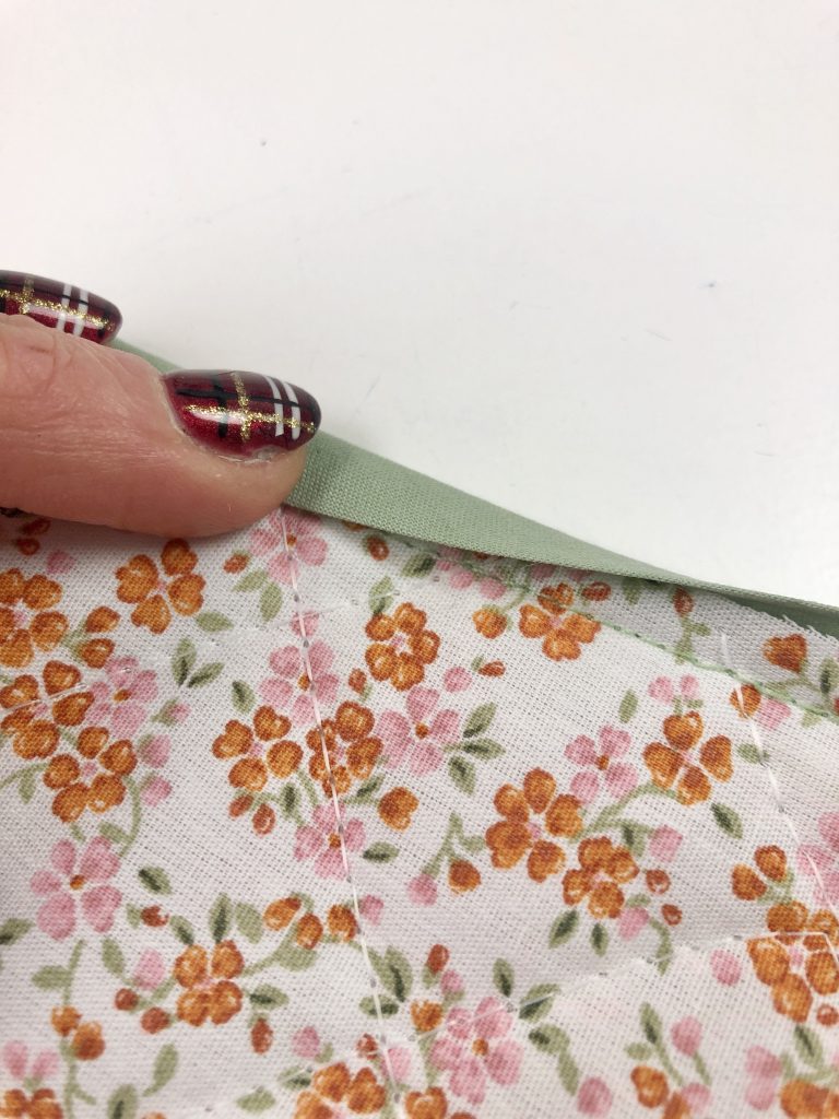 folding the bias binding over the raw edge of the fabric