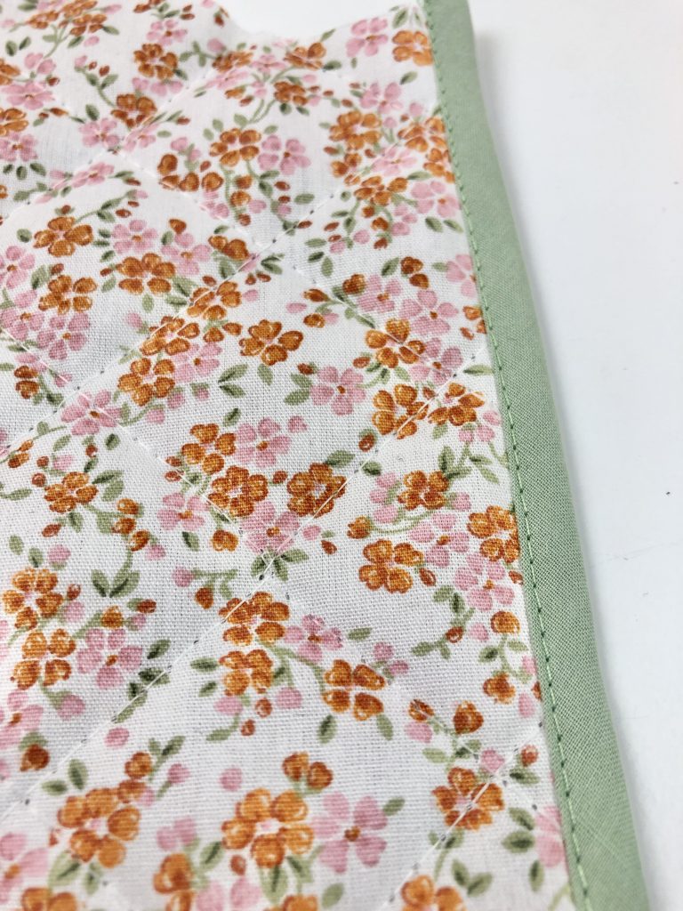 green bias binding stitched to a floral quilted fabric