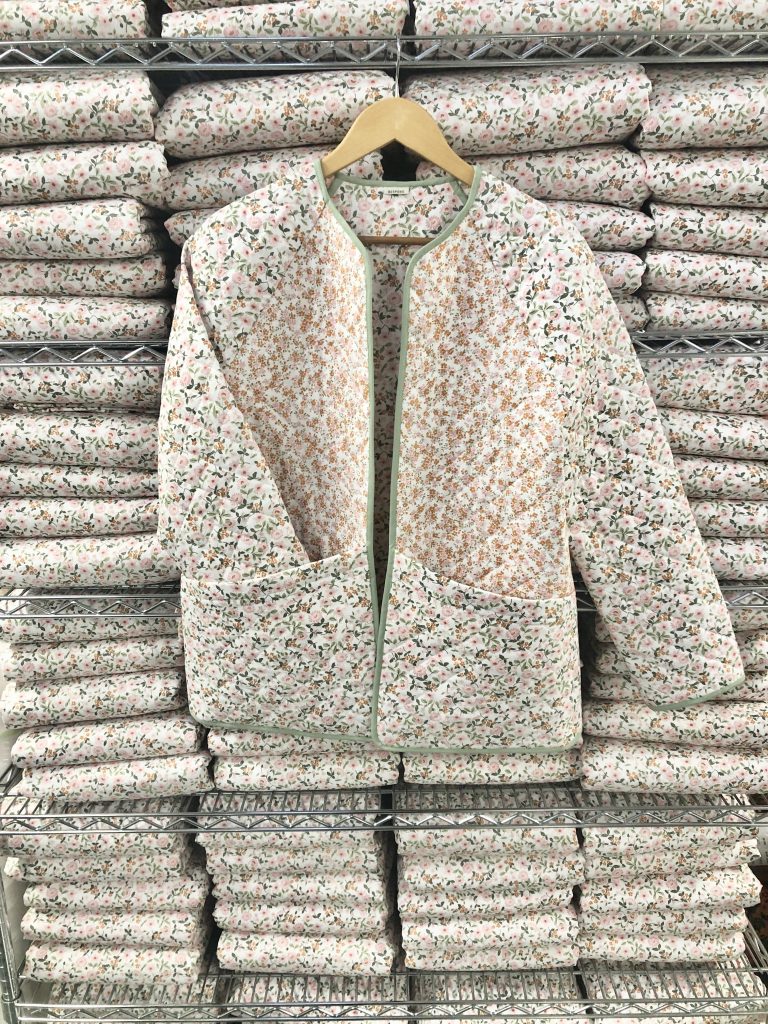 floral quilted jacket in front of shelves of floral quilted fabric