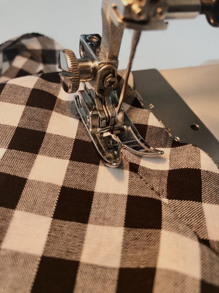 Black gingham fabric being sewn on the sewing machine