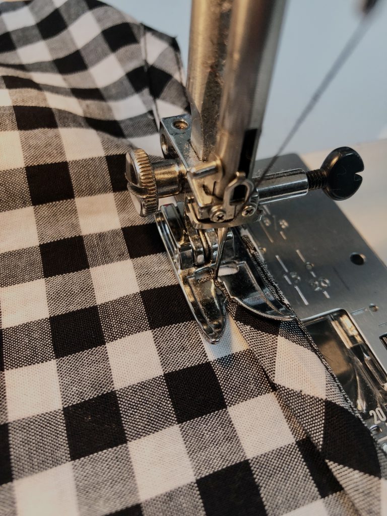 black gingham with binding attached to neckline edge being sewn in place