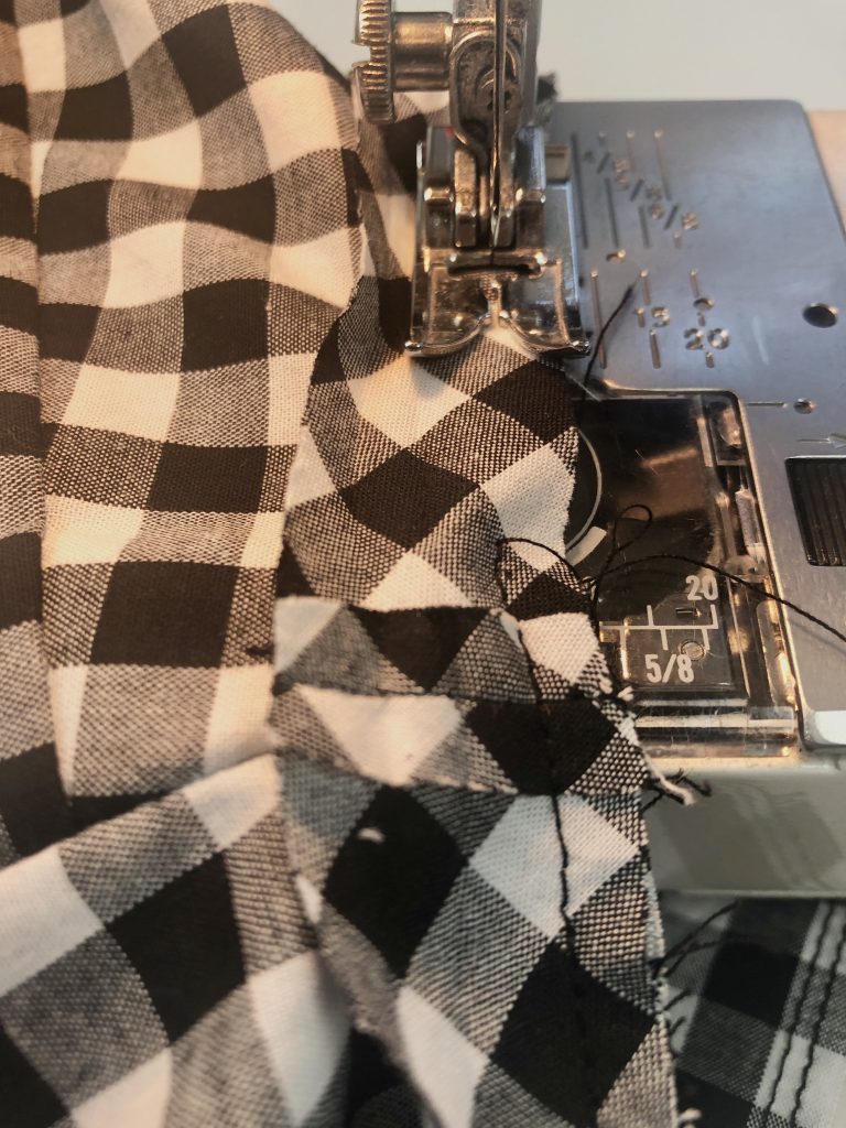 sewing binding to an armhole on black gingham fabric
