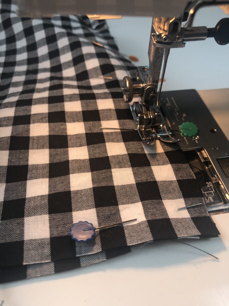 black gingham fabric being sewn on a sewing machine