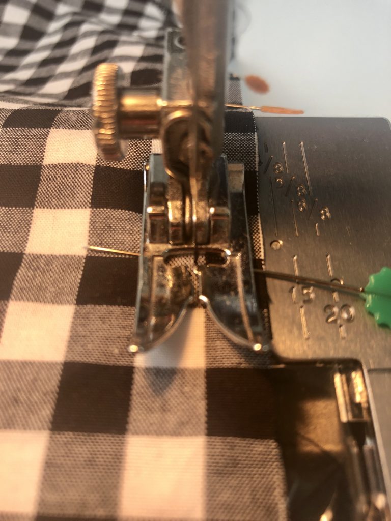 black gingham fabric being sewn on a sewing machine