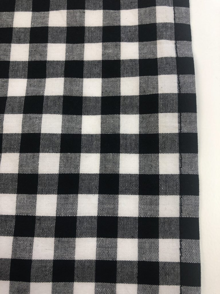 stitching line od hem shown on black gingham fabric
