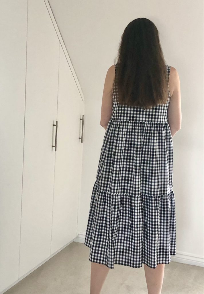 Julia - a white woman wearing the Verano dress - a black and white gingham dress - back view