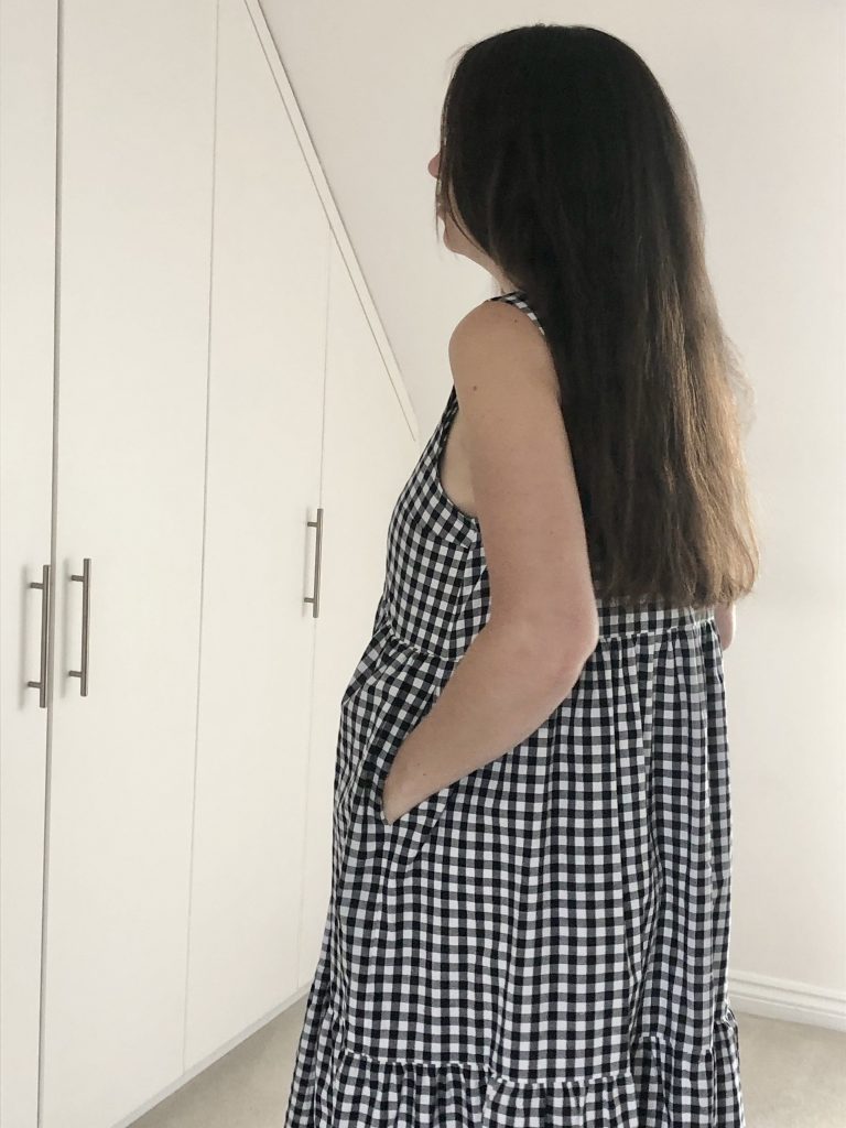 Julia - a white woman wearing the Verano dress - a black and white gingham dress - side view