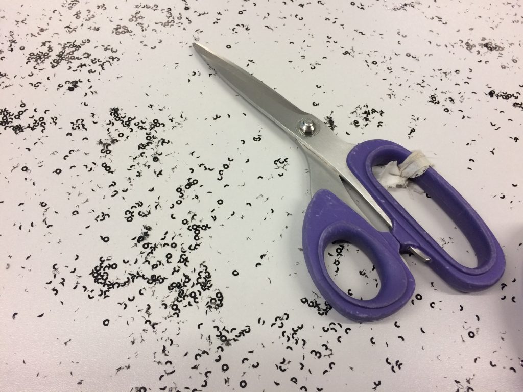 purple handled scissors on a white table with fragments of sequins