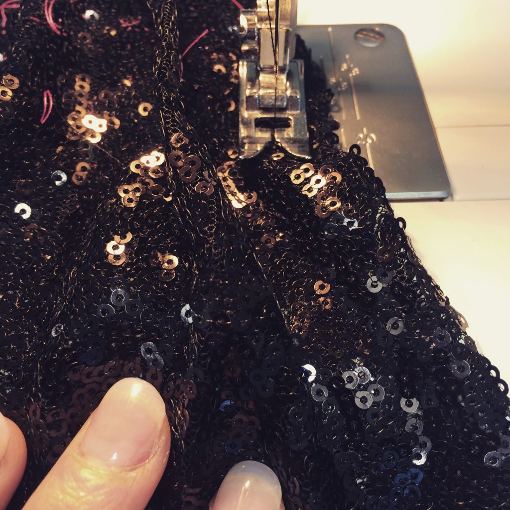 black sequin fabric being sewn on a sewing machine