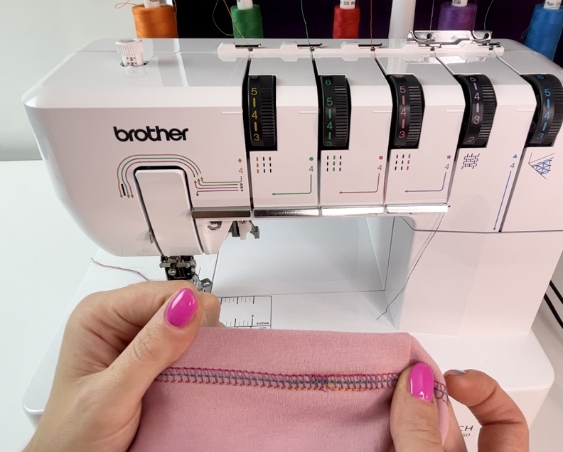 Top coverstitch sewing technique shown on pink sweatshirt fabric with a Brother Coverstitch machine in the background