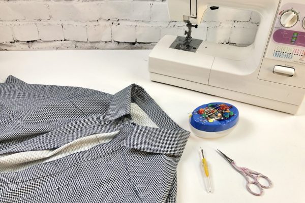 Image of sewing machine with pin cushion, scissors, unpicker and shirt